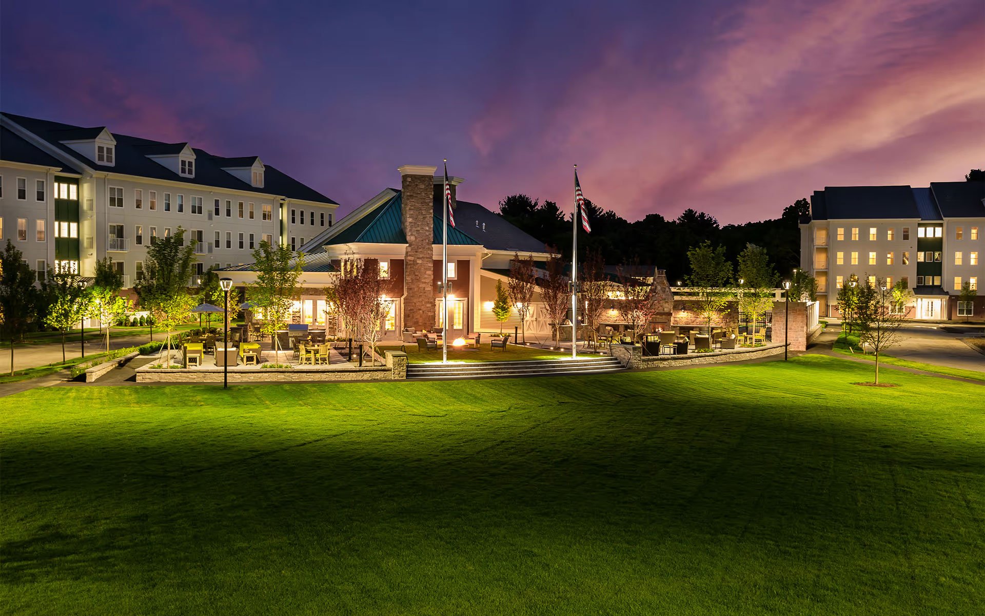 Community green and clubhouse at 1 Upland apartments in Norwood MA at twilight